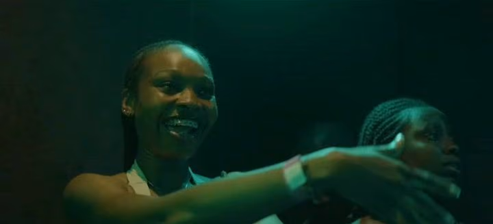 A woman smiles and dances under teal club light at Afro Frequency