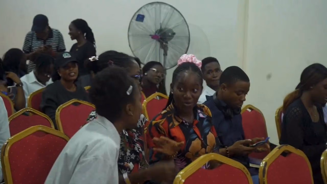 Audience members on red chairs chat between sessions