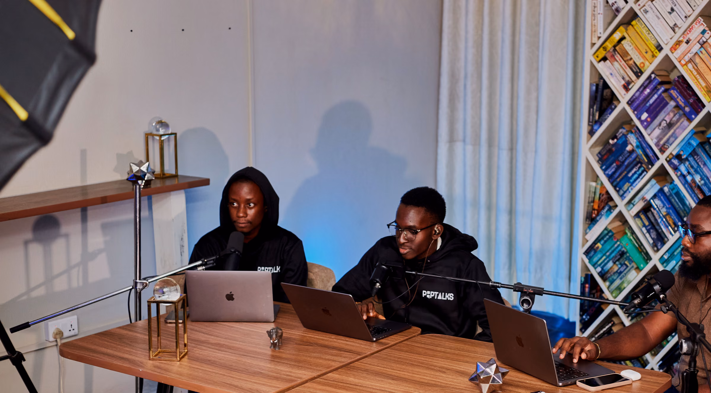 Podcast set with three guests at a table and studio lights