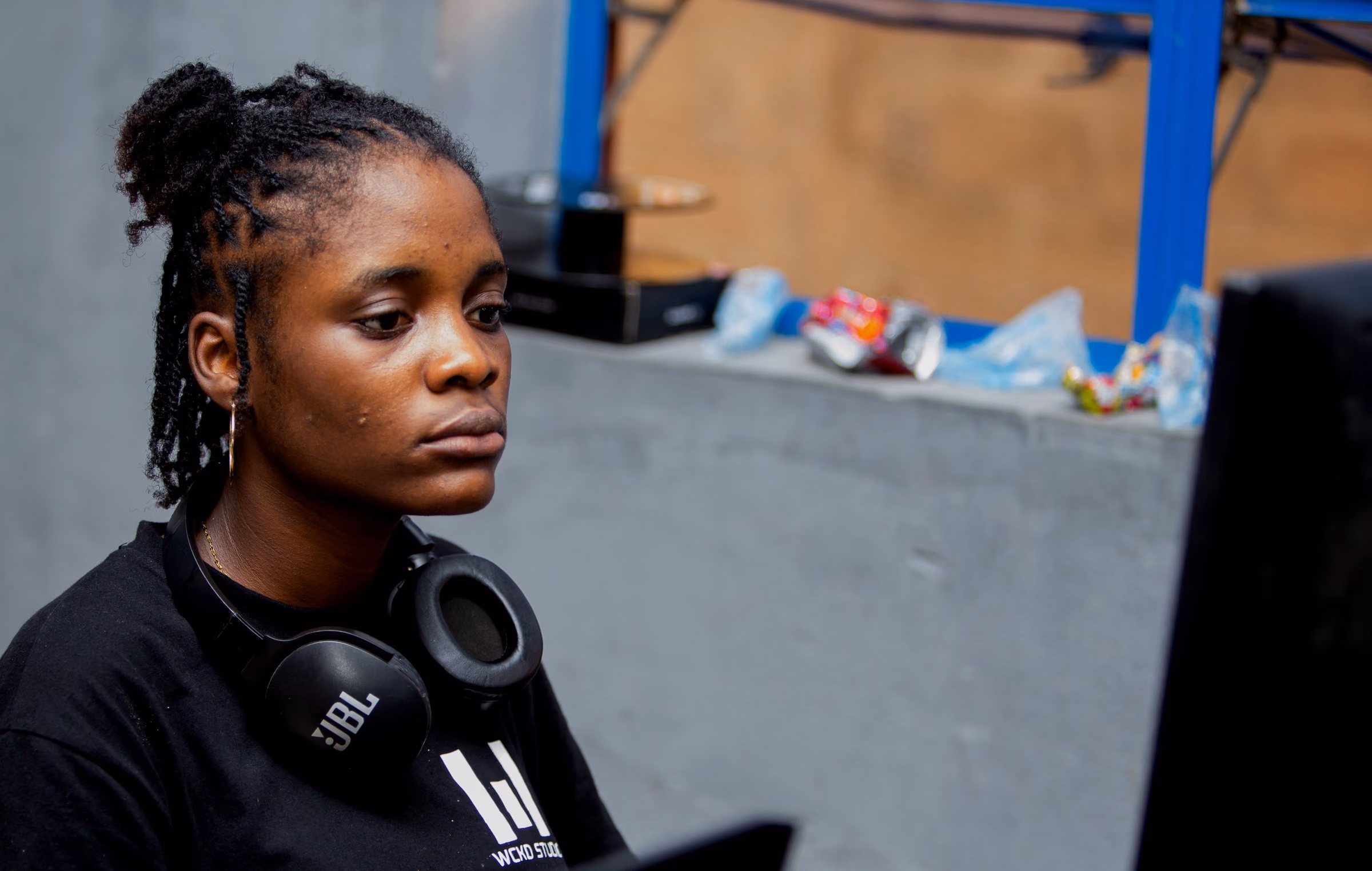 Crew member with headphones looking at a monitor beside a mixer